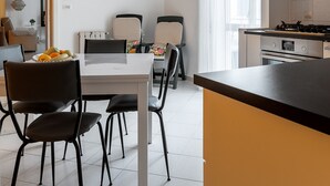 A modern kitchen with a dining area, featuring a white table, black chairs, and a black countertop. - Syracuse Comfy Retreat by Wonderful Italy (Syracuse)