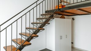 A staircase with wooden steps and metal railings, leading to a white storage unit with cabinets. - Syracuse Comfy Retreat by Wonderful Italy (Syracuse)