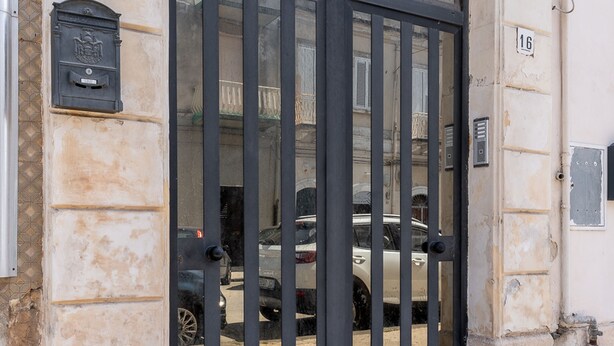 A building entrance with a metal gate, a mailbox, and a number plaque. - Syracuse Comfy Retreat by Wonderful Italy (Syracuse)