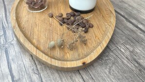 En kold iskaffe i et klart glas med etiket, et mindre glas med chokoladestykker og kaffebønner på en træbakke.