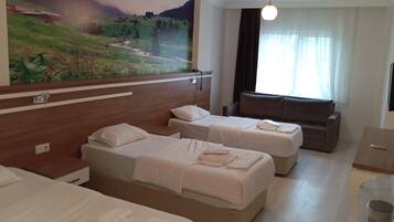A hotel room with three beds, a sofa, a painting of a landscape, and a window with curtains.