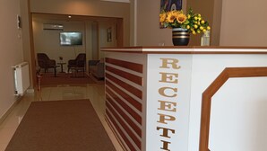 Et receptionsområde med en reception, et brunt gulvtæppe og et maleri hængende på væggen.