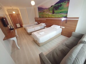 Ein Hotelzimmer mit zwei Einzelbetten, einem Schlafsofa, einem Holzkopfteil, einem Landschaftsbild und einem Fernseher auf einem Lowboard.