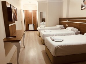 Ein Hotelzimmer mit zwei Betten, einem Schreibtisch, einem Kleiderschrank und einem Fernseher.