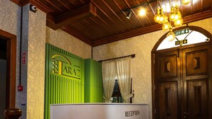 A reception area with a green and white counter, wooden ceiling, and a red carpet. - Araz White House (Mudanya)