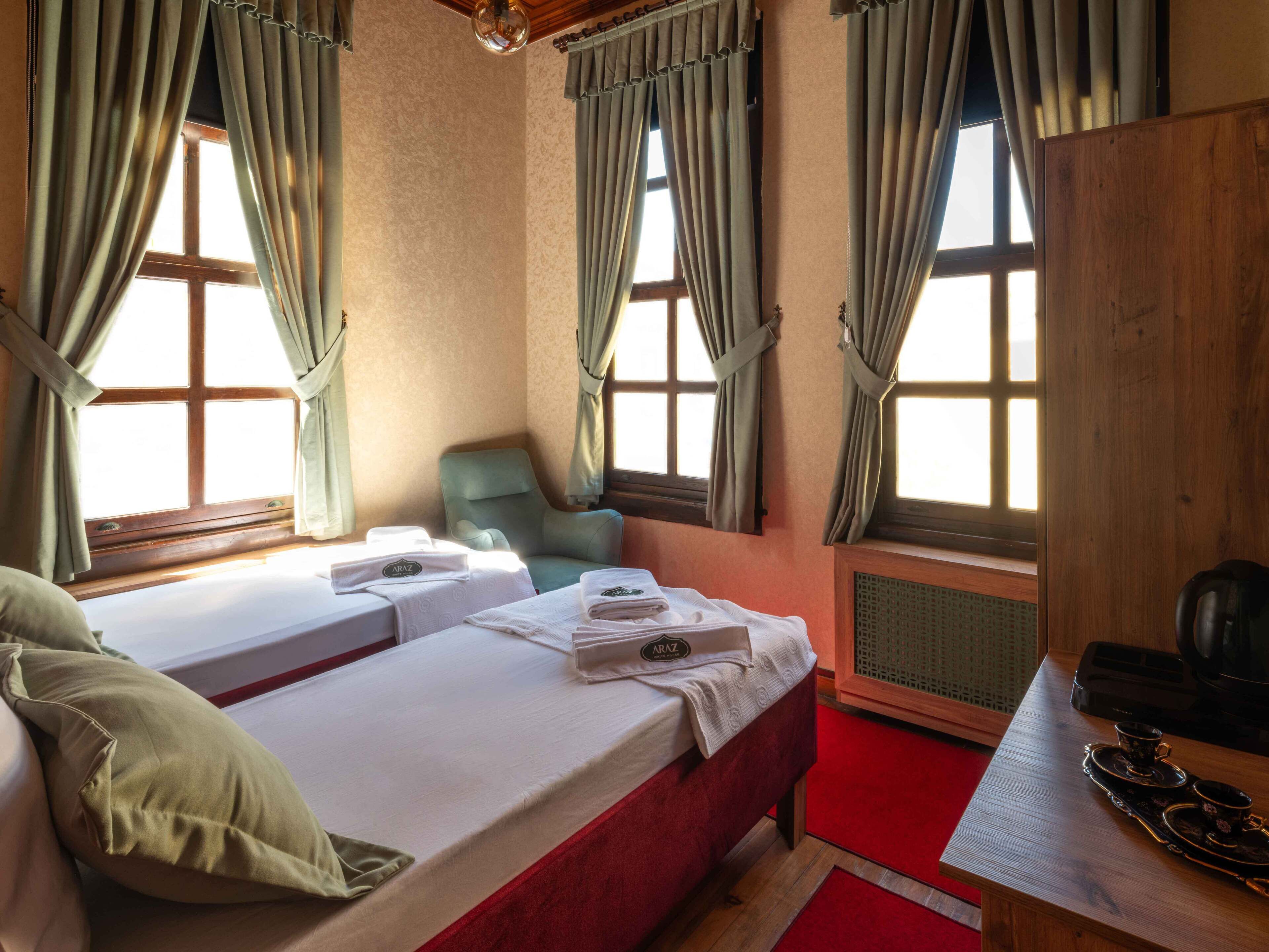 Een hotelkamer met twee bedden, een stoel, een tafel met een dienblad en een radiator.