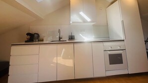 Eine moderne Küche mit weißen Schränken, einem eingebauten Backofen und einem Oberlicht über der Arbeitsplatte.