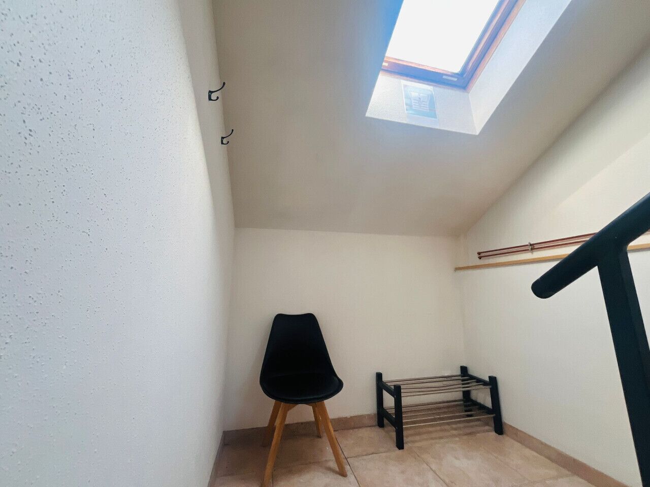 A small room with a skylight, a chair, a bench, and a wooden floor.