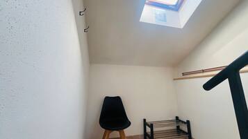 A small room with a skylight, a chair, a bench, and a wooden floor.