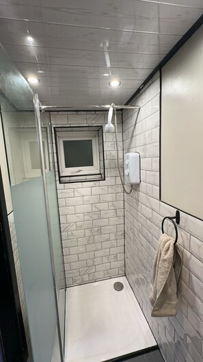 Een douche, handdoeken, zeep, toiletpapier