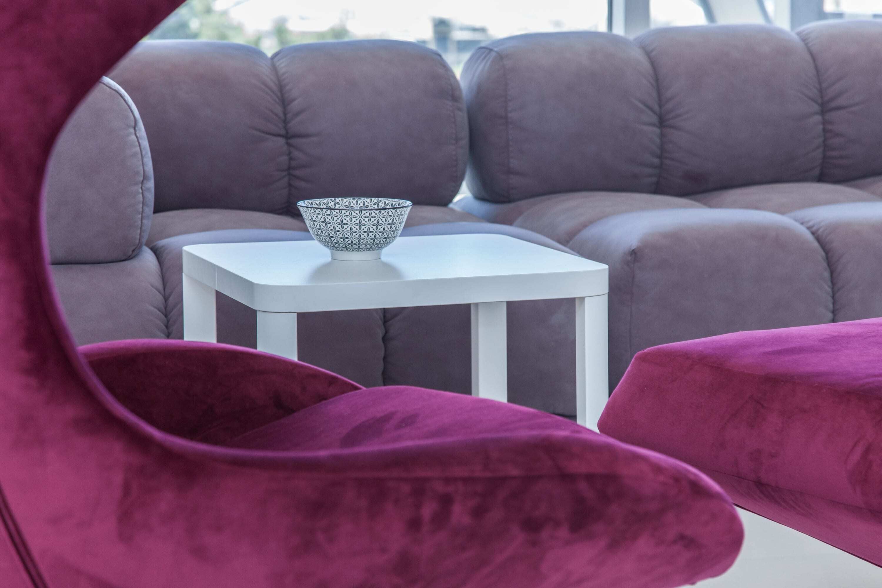 A modern living room with a sectional sofa, a small white table, and a patterned bowl on the table.