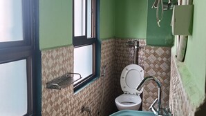 A small bathroom with a toilet, sink, and window. - Our Villa Guest House (Shillong)