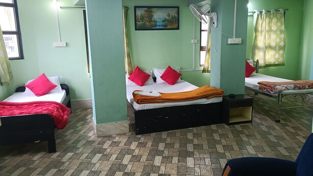 A room with two beds, each with red and white bedding, a painting on the wall, and a ceiling fan. - Our Villa Guest House (Shillong)