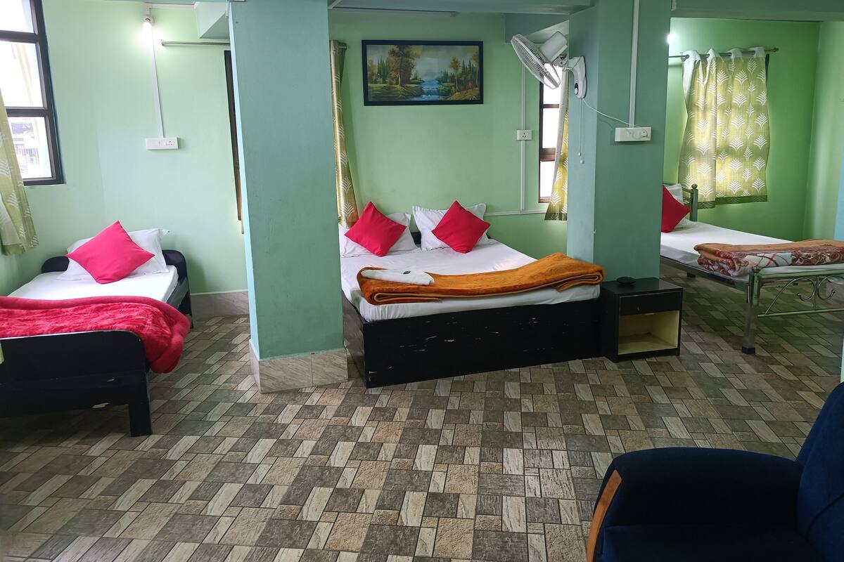A room with two beds, each with red and white bedding, a painting on the wall, and a ceiling fan.