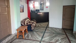 A reception area with a reception desk, a sofa, and a small table. - Our Villa Guest House (Shillong)