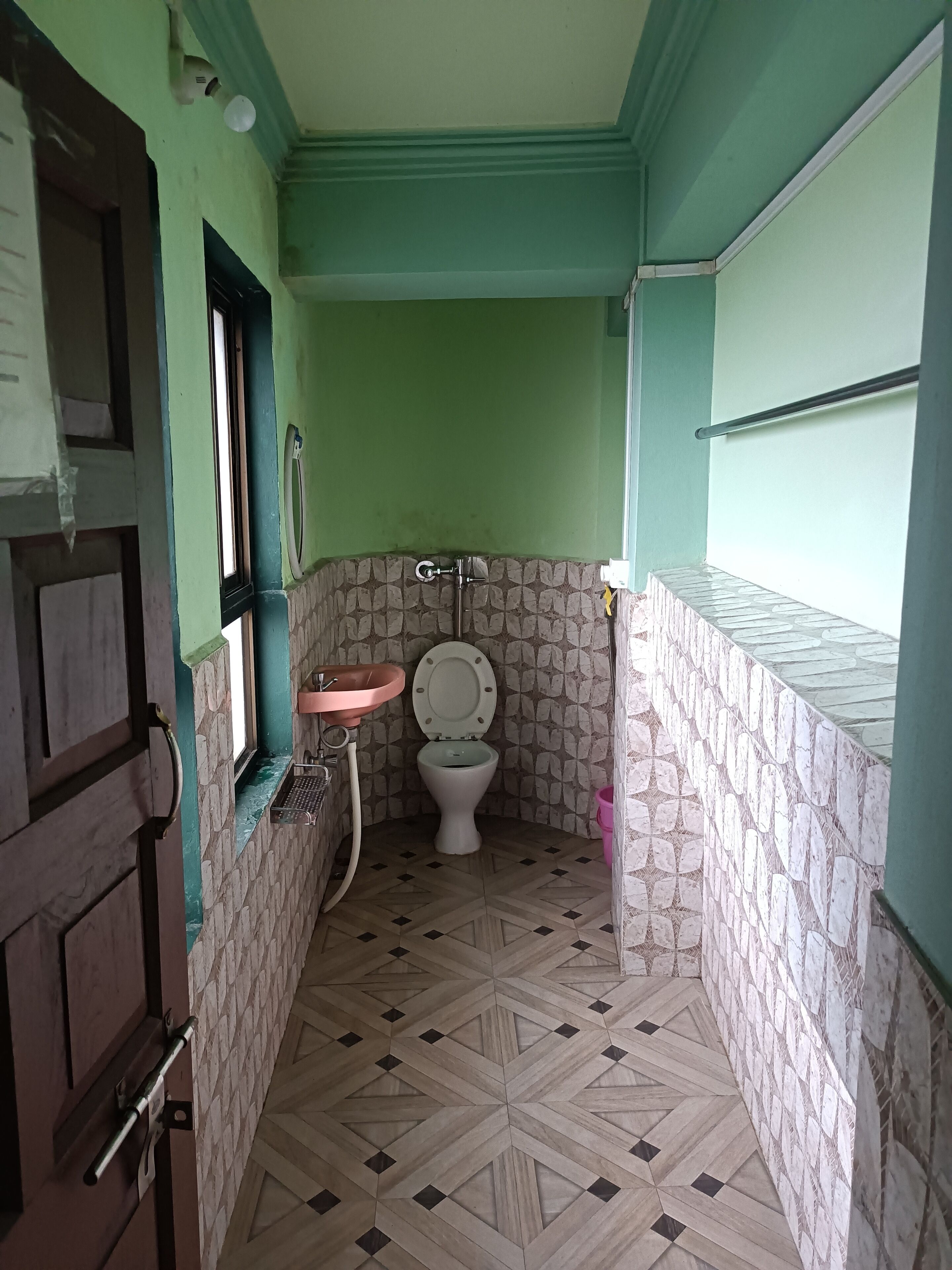 A small bathroom with a toilet, sink, and a window.
