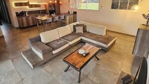 A spacious living area with a sectional sofa, a coffee table, and a kitchen in the background. - Villa Pardisoli 2. Logement Entier : Hébergement - Prunelli-di-fiumorbo, France (Prunelli-di-Fiumorbo)
