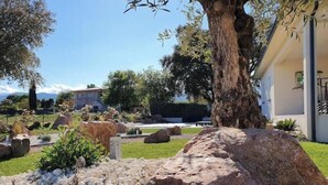 A landscaped garden with large rocks, a tree, and a building in the background. - Villa Pardisoli 2. Logement Entier : Hébergement - Prunelli-di-fiumorbo, France (Prunelli-di-Fiumorbo)