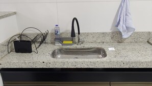 A kitchen with a granite countertop, a stainless steel sink, and a black cabinet.