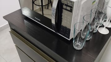 Una cocina moderna con microondas integrado y una estación de café de superficie de vidrio.