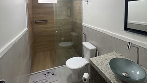A modern bathroom with a glass-enclosed shower, a toilet, and a sink with a marble countertop.