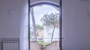 A bedroom with a wooden floor, a bed, a radiator, and a view of the outside. - Wonderful  villa for 5 people with WIFI, A/C, TV, terrace and pets allowed, close to Forte Dei M... (Marina Dei Ronchi)