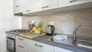 A modern kitchen with a gas stove, stainless steel sink, and wooden cabinetry. - Wonderful  villa for 5 people with WIFI, A/C, TV, terrace and pets allowed, close to Forte Dei M... (Marina Dei Ronchi)