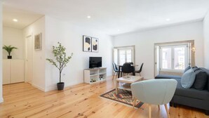 Una sala de estar moderna con un sofá, una mesa de centro, un televisor y un comedor con sillas y una mesa.
