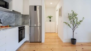 Una cocina moderna con un refrigerador de acero inoxidable, encimera de mármol y suelo de madera.