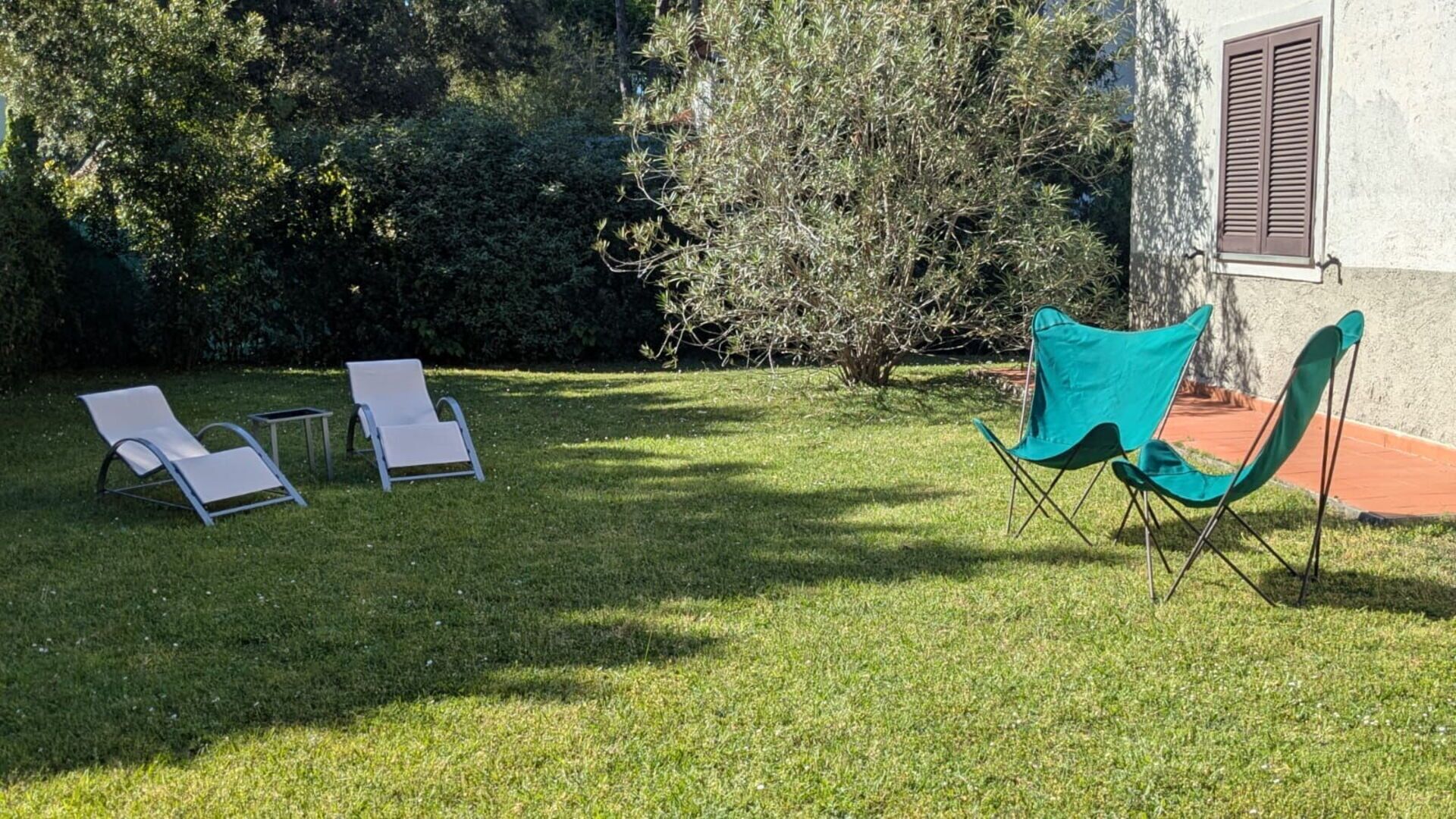 A grassy outdoor area with two lounge chairs and a folding chair.