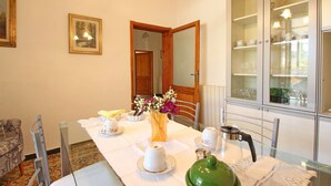 Un comedor con una mesa dispuesta para cuatro personas, un aparador con puertas de vidrio y un cuadro en la pared.