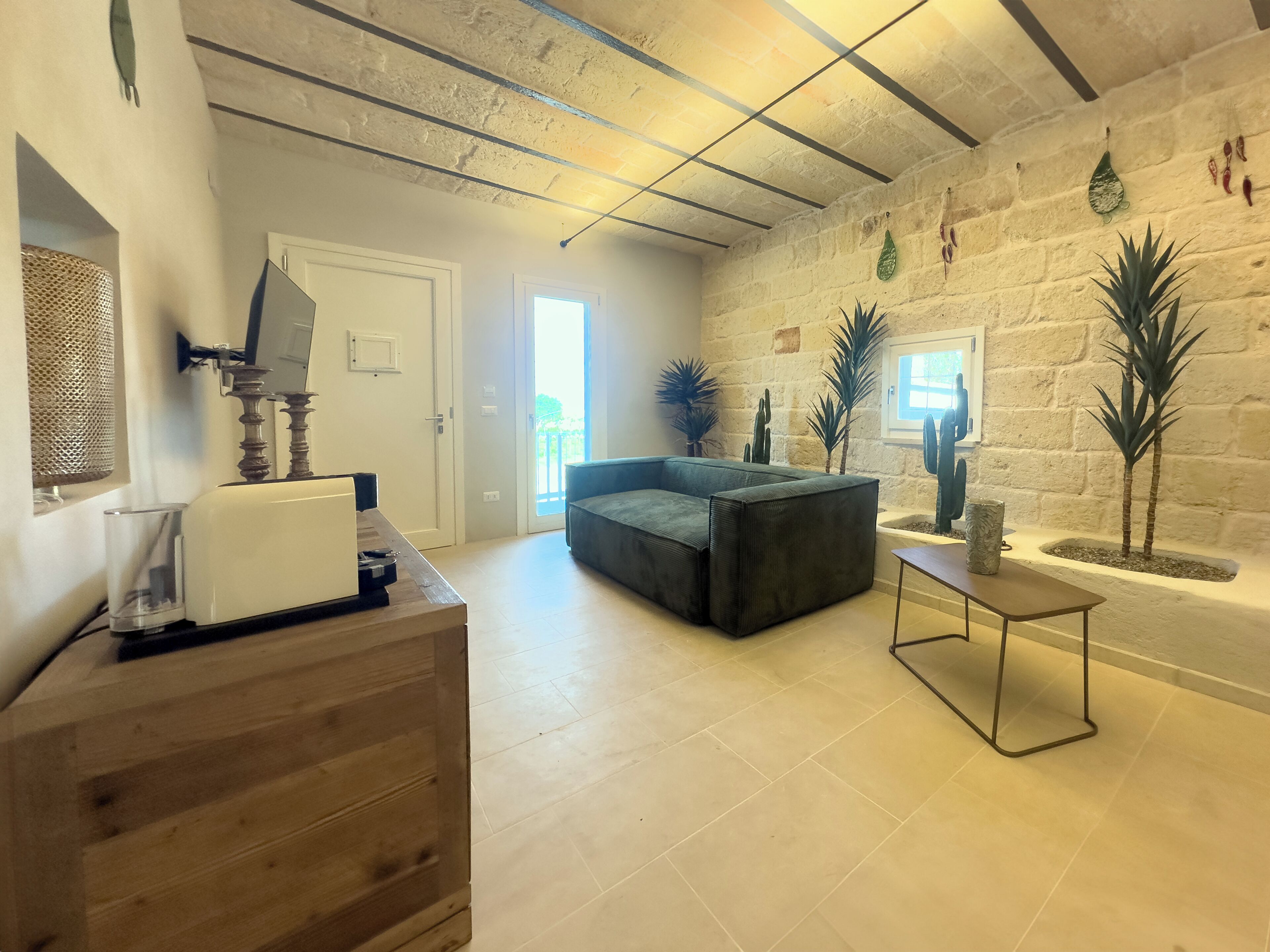 A spacious living area with a large sofa, a wooden coffee table, and a stone wall with plants.