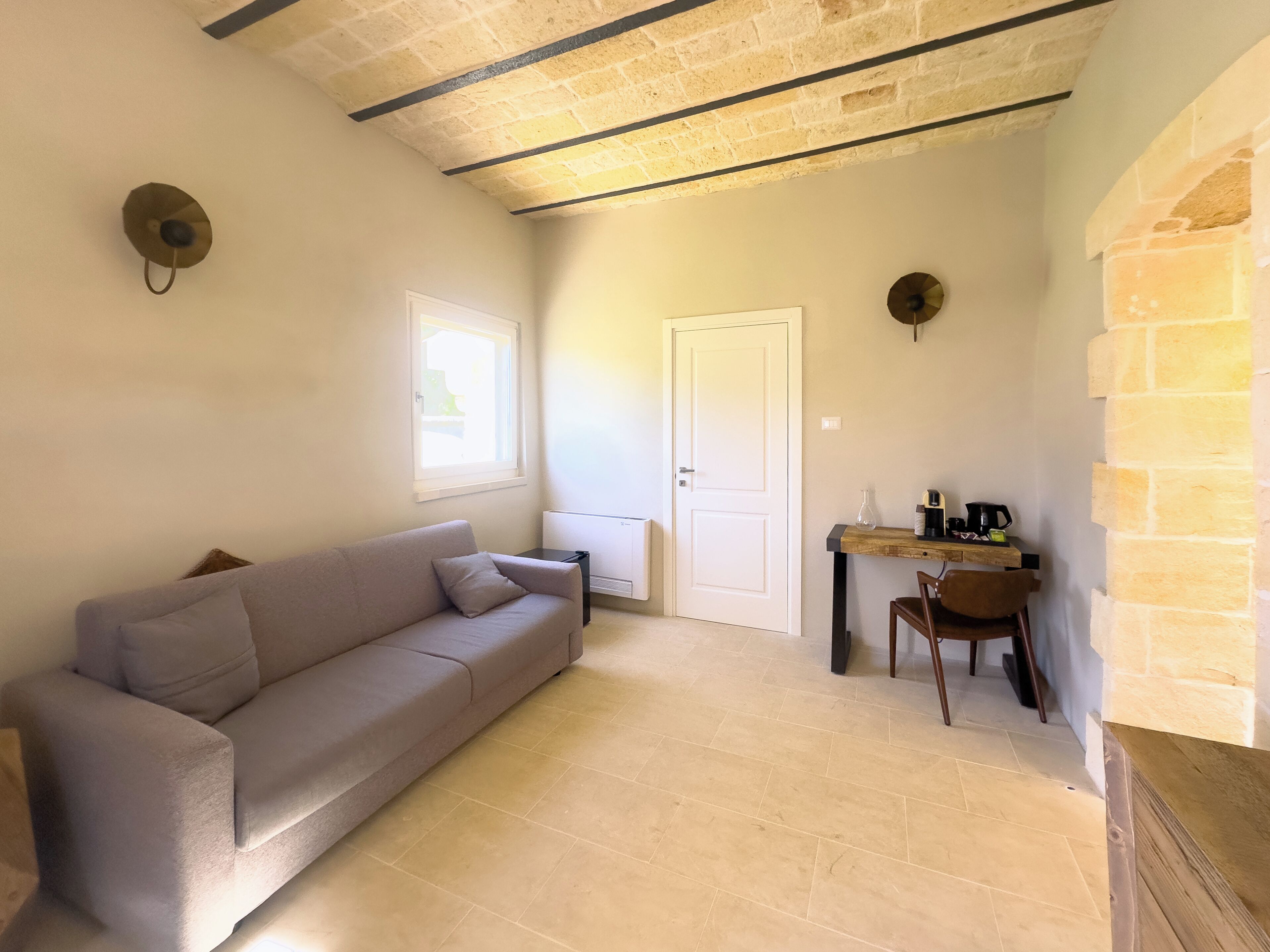 A cozy living area with a sofa, a dining table with chairs, a window, and a door.