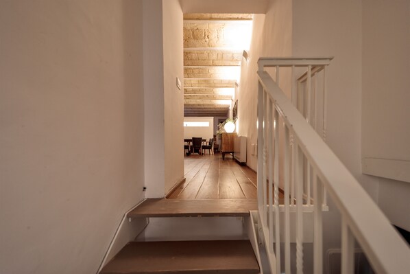 Una escalera conduce a una habitación con piso de madera y barandal blanco.