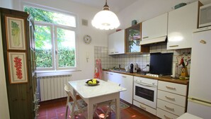 A kitchen with white cabinets, a stove, a sink, and a window with greenery outside.