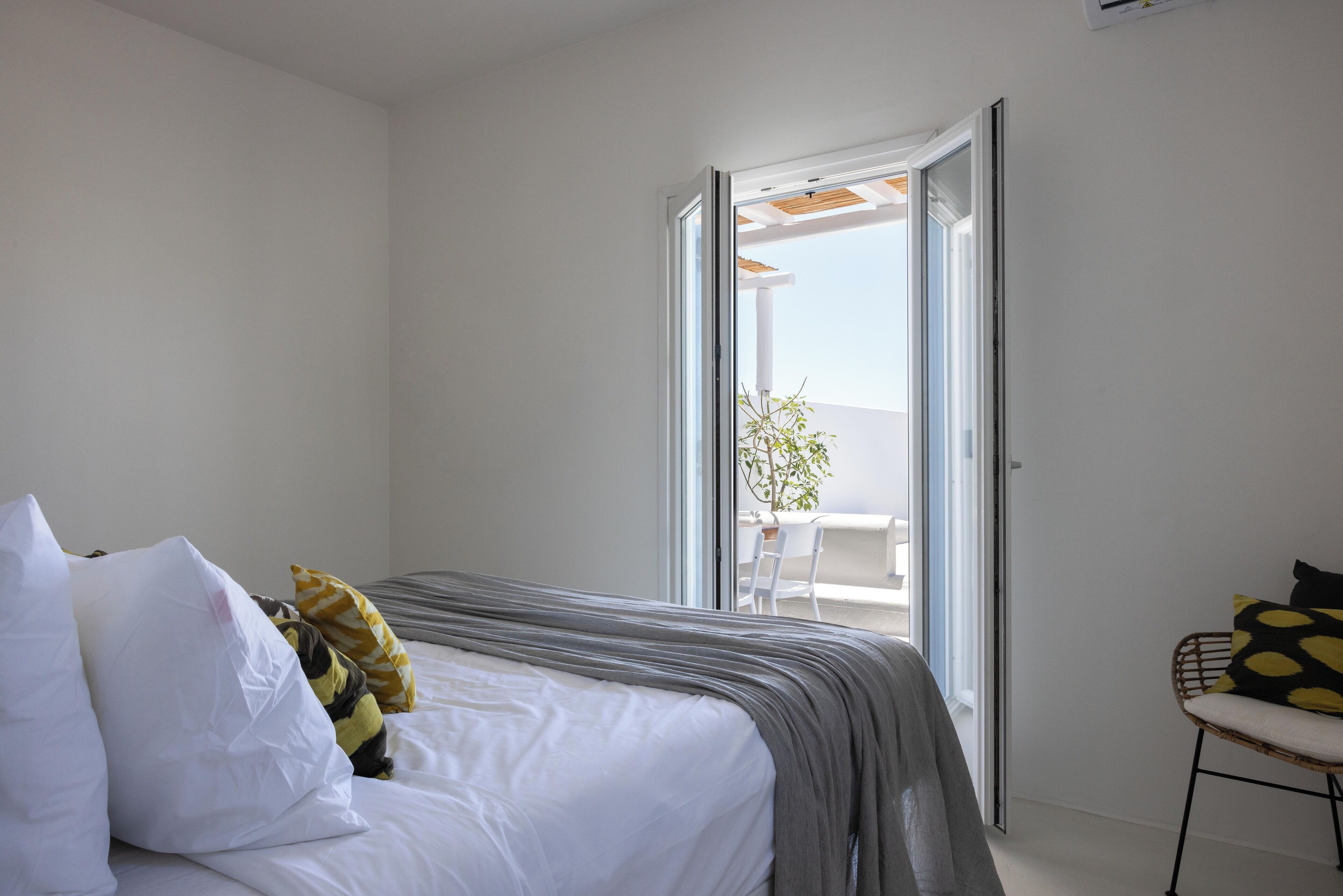 A bedroom with a bed, a chair, and a sliding glass door leading to an outdoor area.