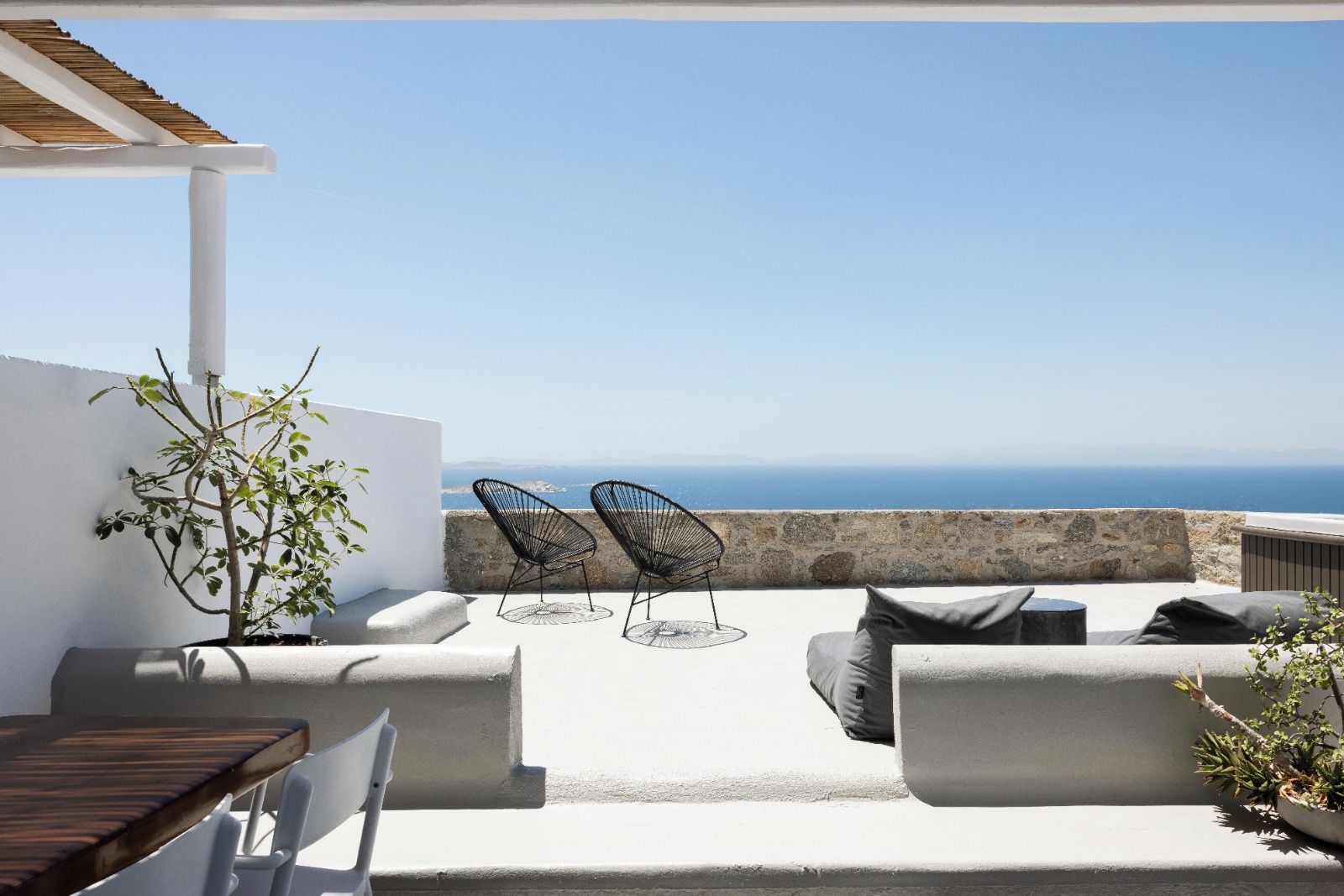 A terrace with a view of the sea, featuring a table, chairs, and a seating area.