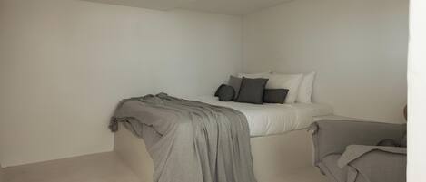 A minimalist bedroom with a bed, pillows, and a blanket.