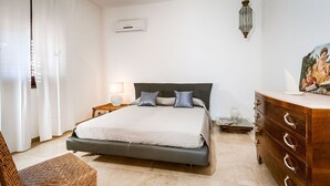 Une chambre à coucher avec un lit, une table de chevet, une lampe, une commode et un tableau au mur.
