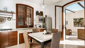 La cuisine est équipée d’une cuisinière à gaz, d’un four à micro-ondes et d’un réfrigérateur. On y trouve également une table à manger avec des chaises en osier.