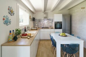 Eine kompakte Küche mit Kochinsel, einem Essbereich mit Stühlen und einem Kühlschrank.