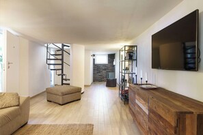 Una sala de estar moderna con una escalera espiral, un sofá, un televisor y una estantería.