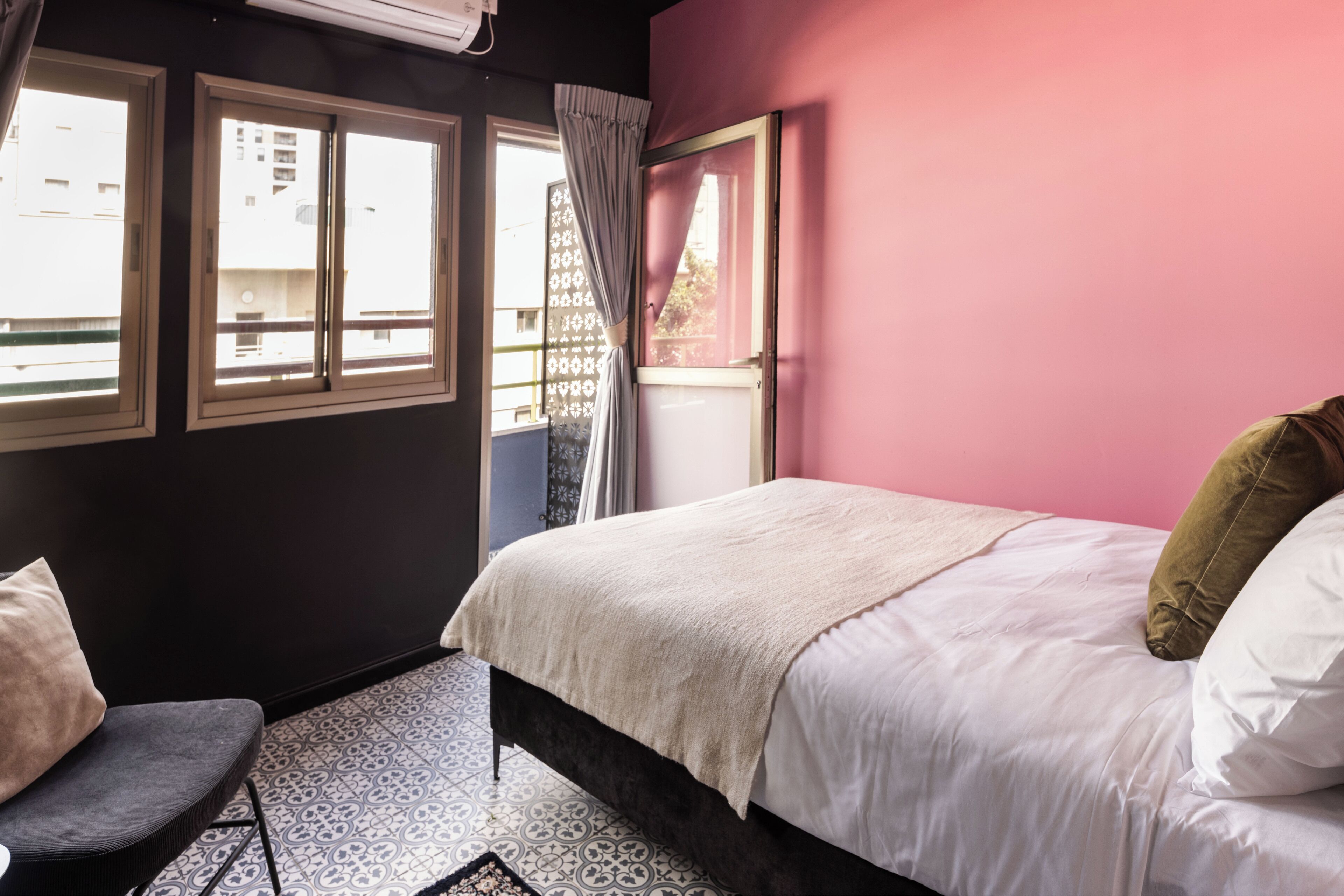 A bedroom with a bed, a chair, and a window with curtains.