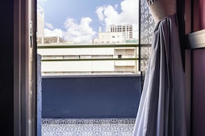 Vista desde un balcón con baldosas estampadas y un edificio al fondo.