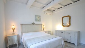 A bedroom with a large bed, two bedside tables with lamps, a dresser, a ceiling fan, and a wall-mounted mirror.