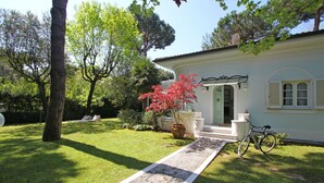 A house with a gravel pathway leading to a porch, surrounded by a well-maintained lawn and trees.