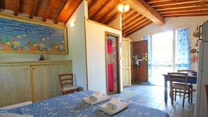 A bedroom with a bed, a wooden ceiling, a painting of fish, a bathroom with a shower, and a dining area with chairs. - Beautiful private villa for 3 guests with A/C, hot tub, TV, veranda, pets allowed and panoramic ... (Castiglione Della Pescaia)