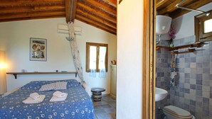 A bedroom with a bed, a bedside table, a window with curtains, and a bathroom with a toilet and sink. - Beautiful private villa for 3 guests with A/C, hot tub, TV, veranda, pets allowed and panoramic ... (Castiglione Della Pescaia)