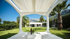 En vit pergola med utsikt över ett modernt hus och berg i bakgrunden.