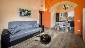 A living room with a sofa, a glass coffee table, and a dining area with a table and chairs. - Beautiful private villa for 8 guests with private pool, WIFI, A/C, TV, veranda and panoramic view (Castellammare Del Golfo)